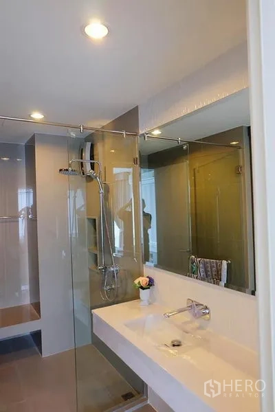 Condominium for rent in Khlong Toei, Bangkok - Bathroom vanity and walk-in shower with rain showerhead and recessed lighting.