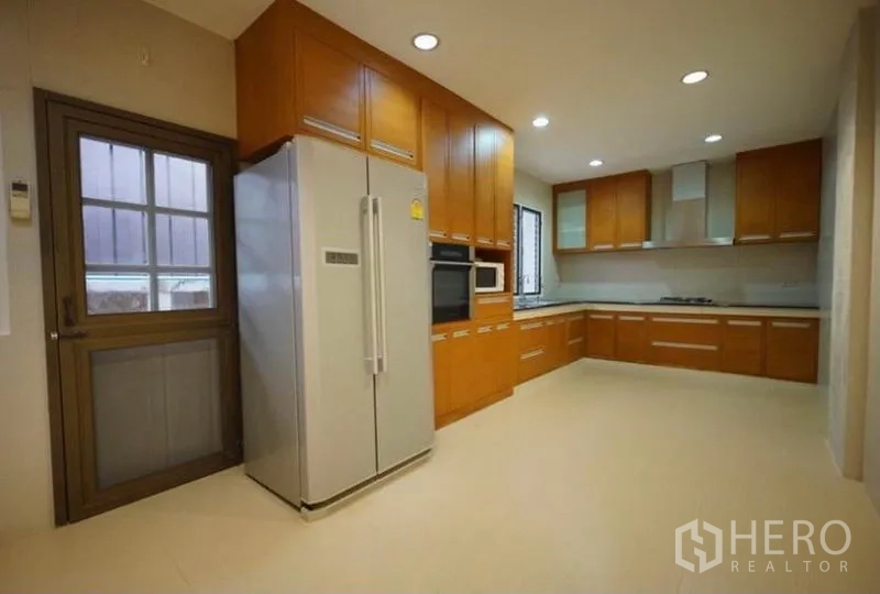 Detached House for rent in Bang Phli, Samut Prakan - Modern L-shaped kitchen with wood cabinetry, built-in oven and double-door fridge.