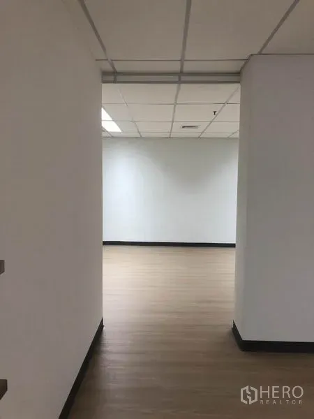 Office Space for rent in Watthana, Bangkok - Hallway leading to an open-plan office area with white walls and vinyl flooring in the Asok area.