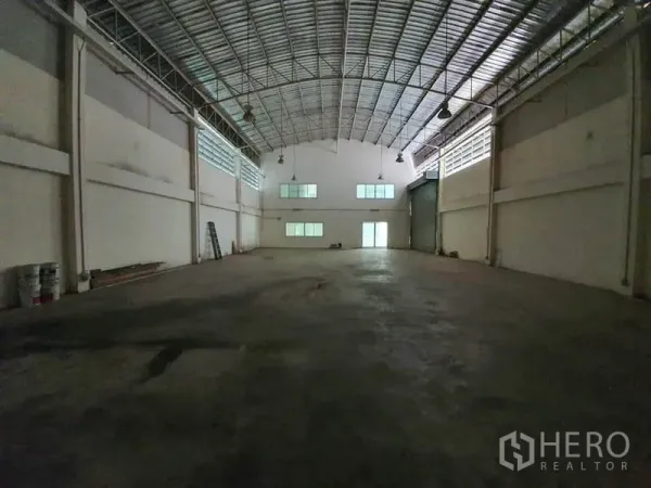 Factory for rent in Lam Luk Ka, Pathum Thani - Open factory floor with column-free space, skylights, hanging lights and rear loading access.