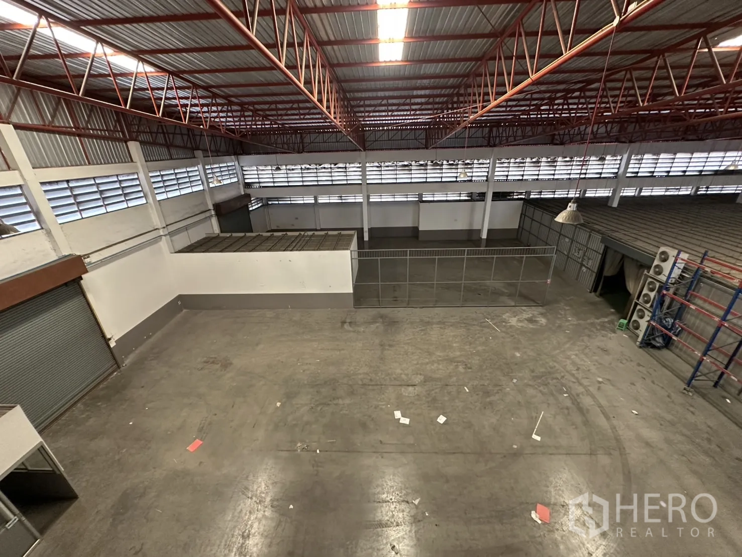 Factory for rent - Aerial view across the warehouse floor and fenced zone beneath skylights.