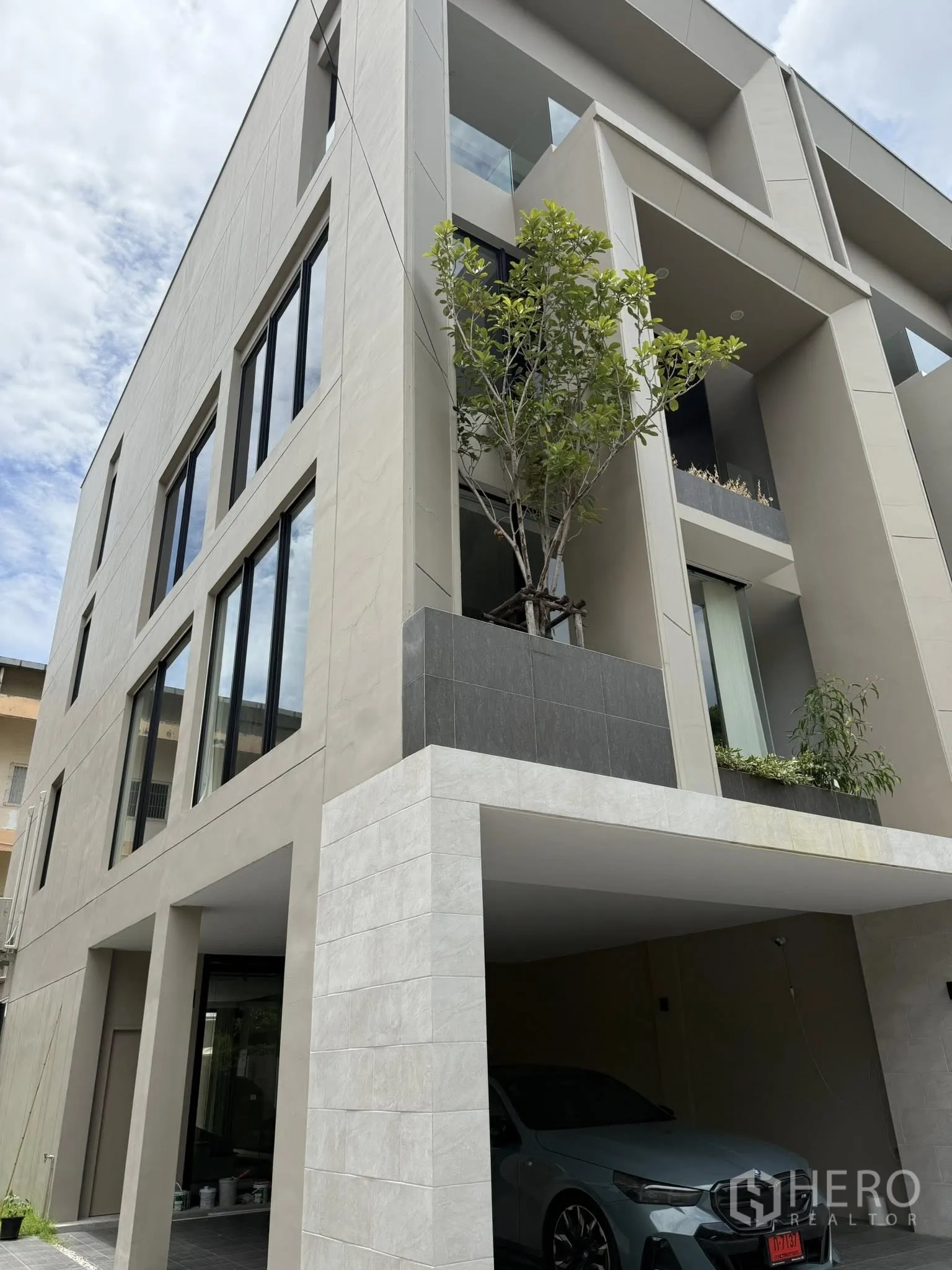 Home Office for rent or sale in Lat Phrao, Bangkok - Modern four-storey home office facade with large windows, balconies and covered parking on a main road.