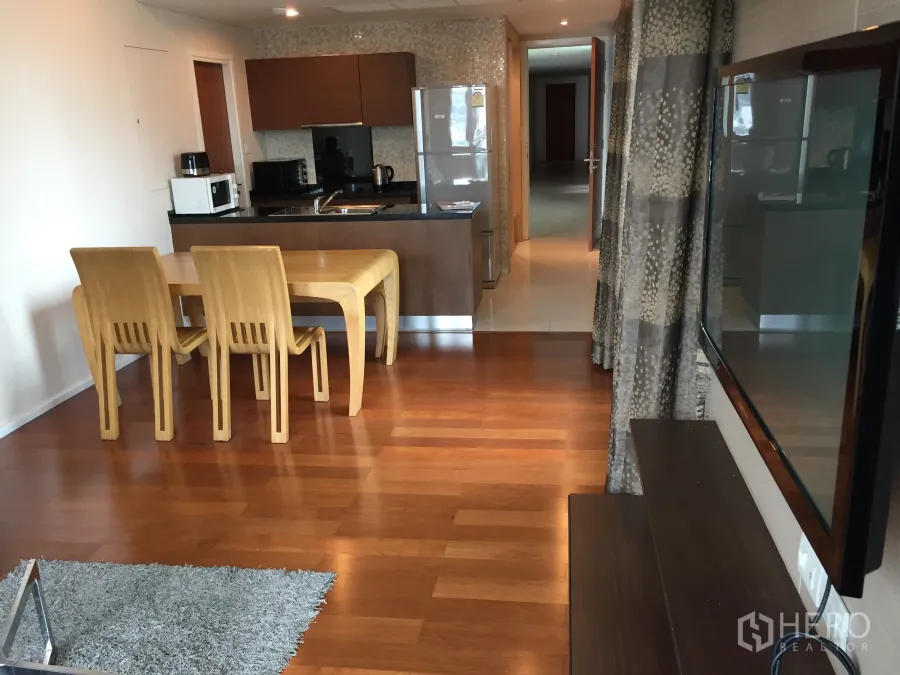 Condominium for rent or sale in Watthana, Bangkok - Open-plan kitchen and dining with wood floors, modern appliances and corridor in a Bangkok condo.