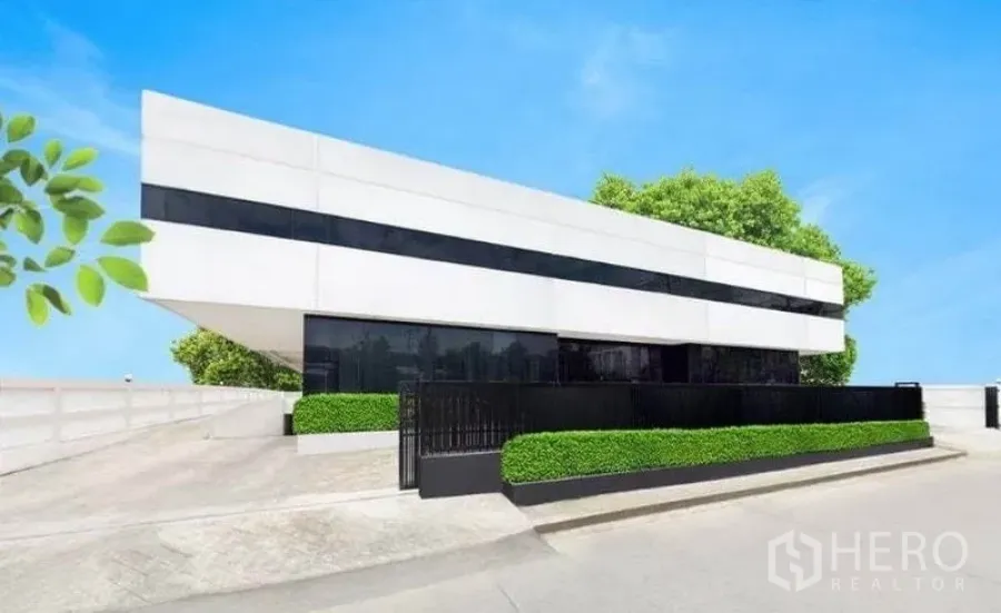 Warehouse for rent in Bang Phli, Samut Prakan - Modern white industrial building exterior with black ribbon windows, secure gate and trimmed hedges.