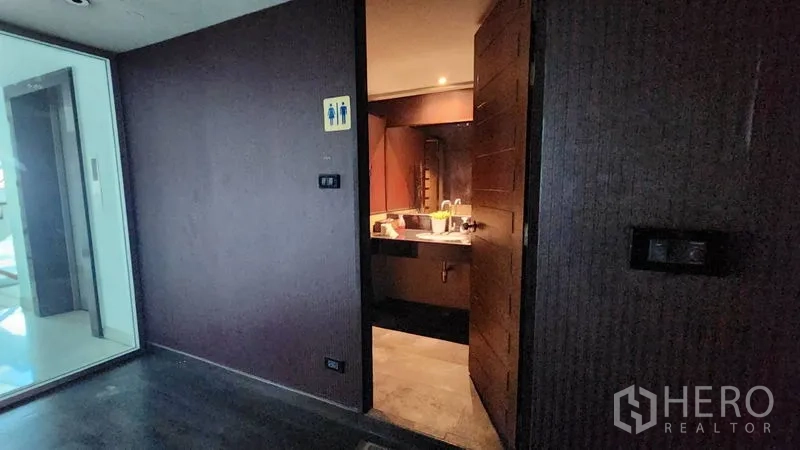 Shophouse for rent in Khlong Toei, Bangkok - Entrance to a restroom with sink and signage inside the commercial shophouse.