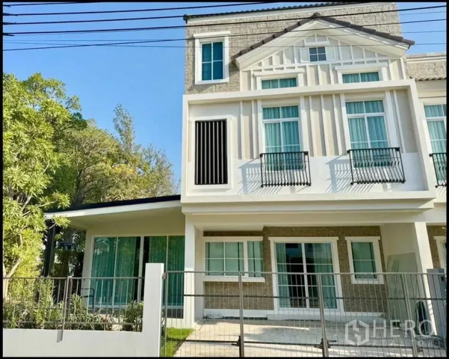 Townhouse for rent or sale in Prawet, Bangkok - Contemporary three‑storey townhouse exterior with tall windows and a small front yard.