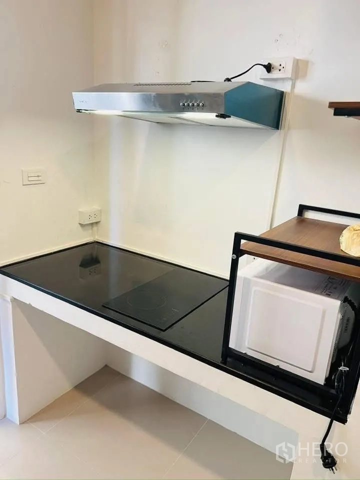 Detached House for rent in Prawet, Bangkok - Kitchen corner with electric hob, stainless range hood and microwave shelf.