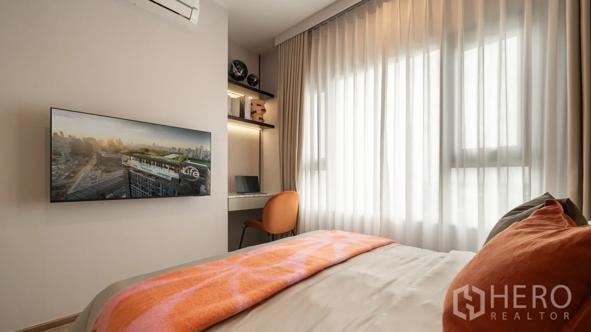 Condominium for sale in Khlong Toei, Bangkok - Second bedroom angle showing wall-mounted TV, built-in study nook, and sheer curtains.