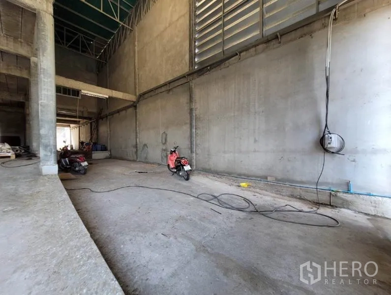 Warehouse for rent or sale in Sai Noi, Nonthaburi - Spacious warehouse bay with high ceiling, louvered ventilation panels, and concrete floor for loading.
