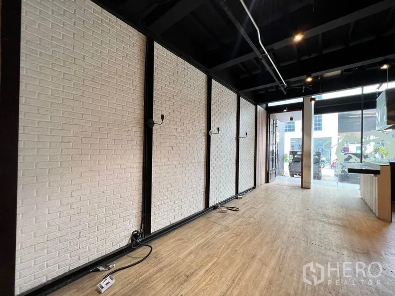 Shophouse for rent - White brick feature wall inside the storefront facing the glass entrance.
