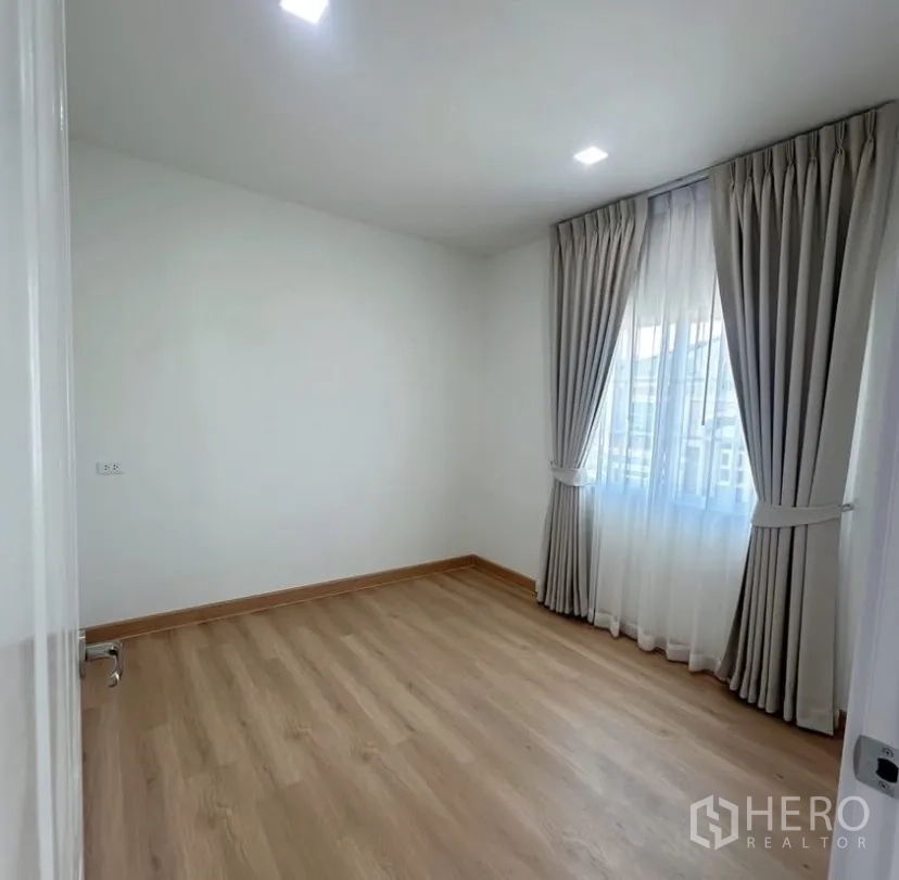 Detached House for rent in Mueang Samut Prakan, Samut Prakan - Sunlit bedroom with light wood flooring, white walls and a curtained window.