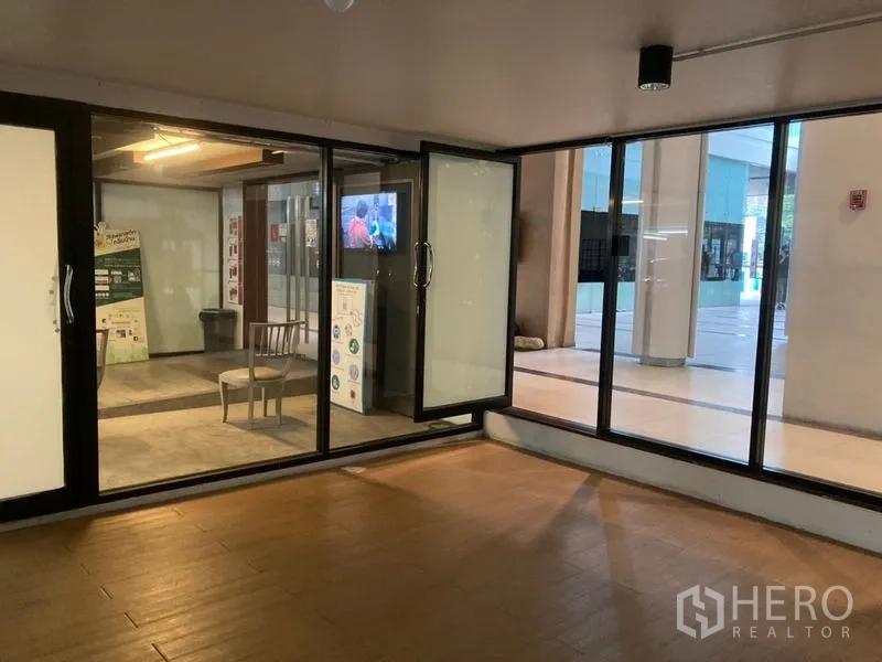 Retail Space for rent in Khlong Toei, Bangkok - Interior view toward the glass entry opening to a covered plaza, with wood-look floors.