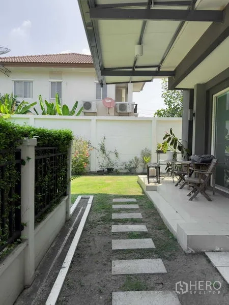 Detached House for rent or sale in Bang Khen, Bangkok - Covered terrace leading to a small garden with stepping-stone path and white fence.