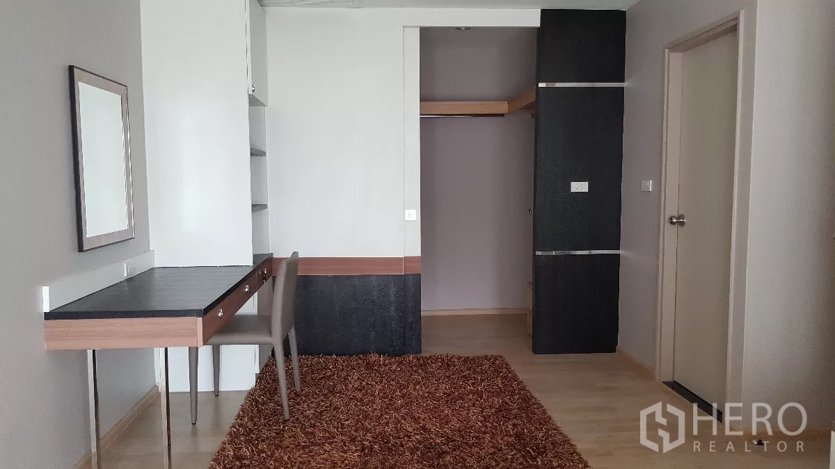 Condominium for rent in Khlong Toei, Bangkok - Study or bedroom with built-in desk, shelving, wardrobe and shag rug flooring.