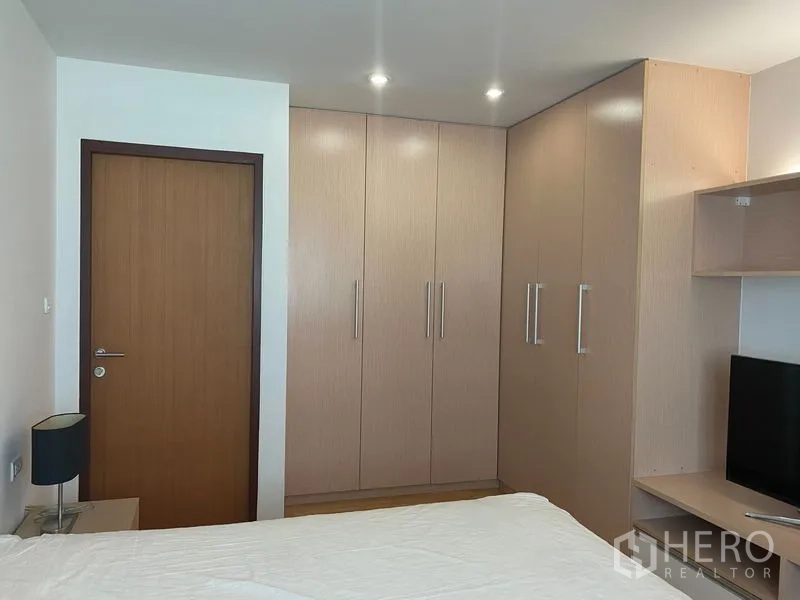 Condominium for rent or sale in Khlong Toei, Bangkok - Corner of bedroom with full-height built-in wardrobes and recessed ceiling lights.