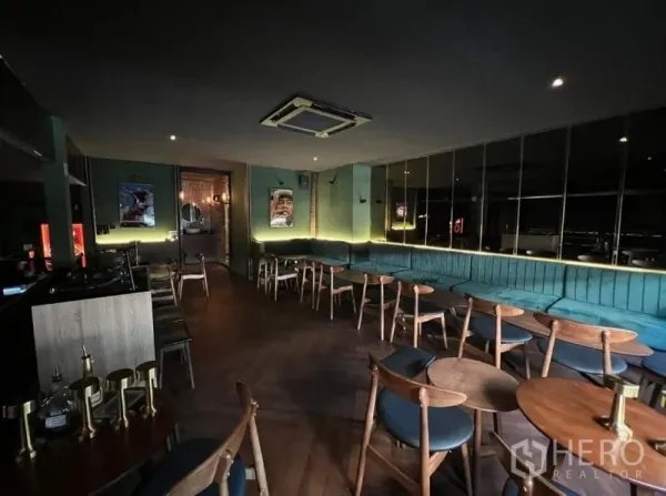 Retail Space for rent in Watthana, Bangkok - Lounge area featuring teal banquette seating, wood tables and a mirrored wall with ceiling AC.