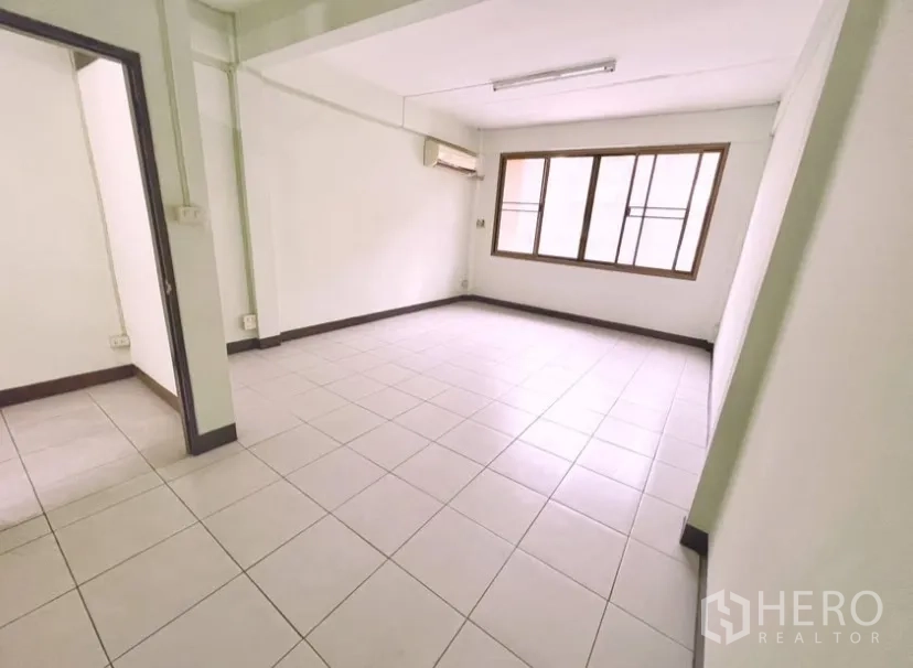 Shophouse for rent in Suan Luang, Bangkok - Bright room with large window and wall-mounted air conditioner.