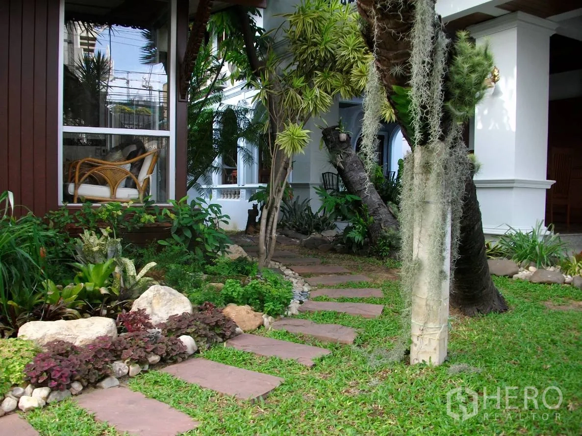 Detached House for rent in Khlong Toei, Bangkok - Lush front yard with stepping stones, tropical plants and patio seating by wide windows.