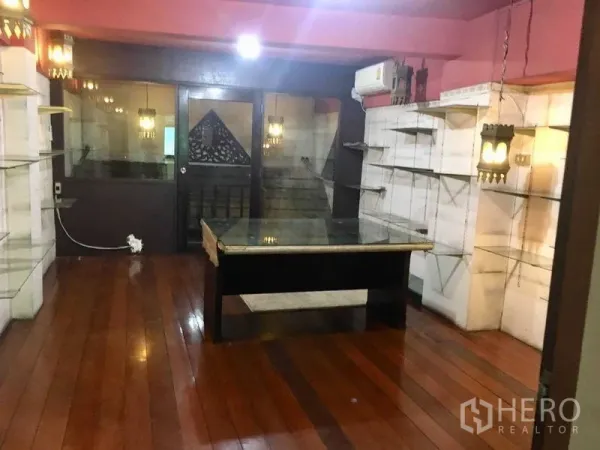 Shophouse for rent in Suan Luang, Bangkok - Ground-floor retail area with wooden floors, glass door, wall display shelves and accent lighting.