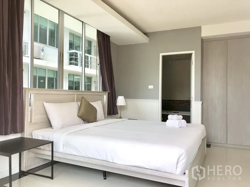 Condominium for rent in Khlong Toei, Bangkok - Primary bedroom with large windows, built-in wardrobe and ensuite bathroom access.