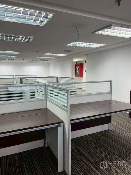 Office Space for rent - Open-plan workspace with cubicles, overhead lighting, and carpet tiles.