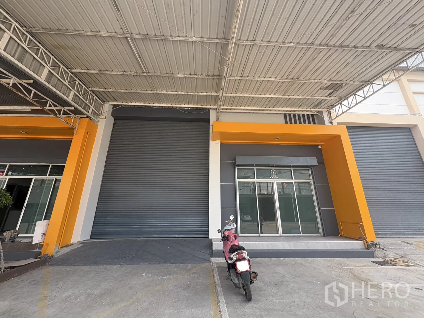 Factory for rent in Phra Samut Chedi, Samut Prakan - Factory frontage with large roller shutter, glass office entrance and covered loading bay.