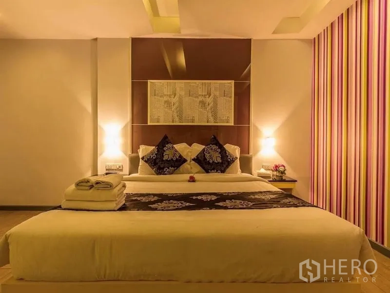 Shophouse for rent or sale in Khlong Toei, Bangkok - Spacious king bedroom with striped accent wall, bedside lamps, and soft linens.