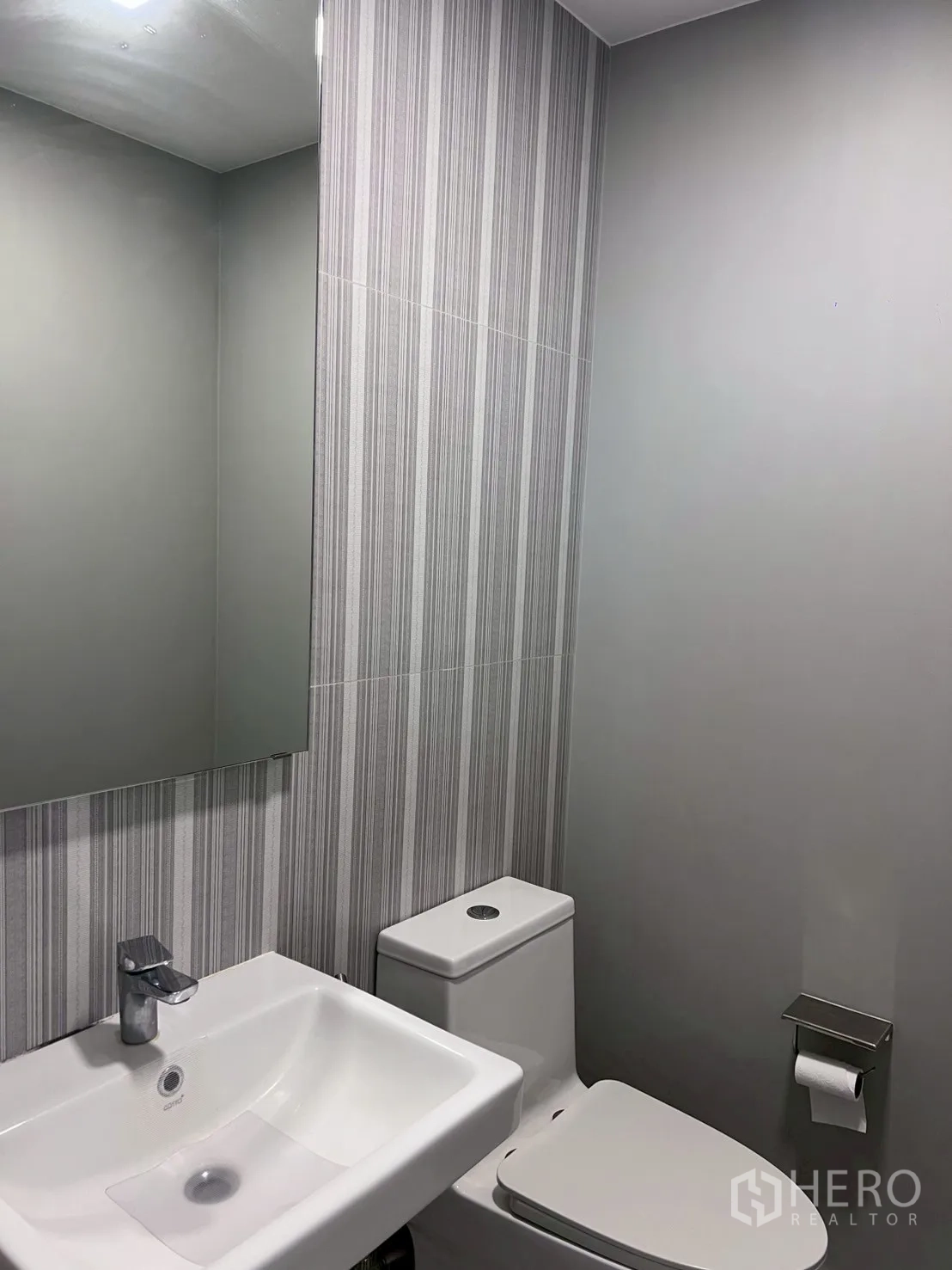 Townhouse for rent in Bang Phli, Samut Prakan - Powder room with striped tiles, mirror, and compact basin.