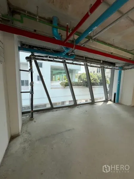 Retail Space for rent in Pathum Wan, Bangkok - Unfinished retail unit with angled windows and exposed pipes and ducts.