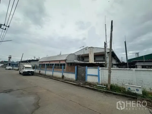 工厂 出售在Khlong Luang, Pathum Thani - 工厂临街外观，围墙与大门沿工业道路分布。