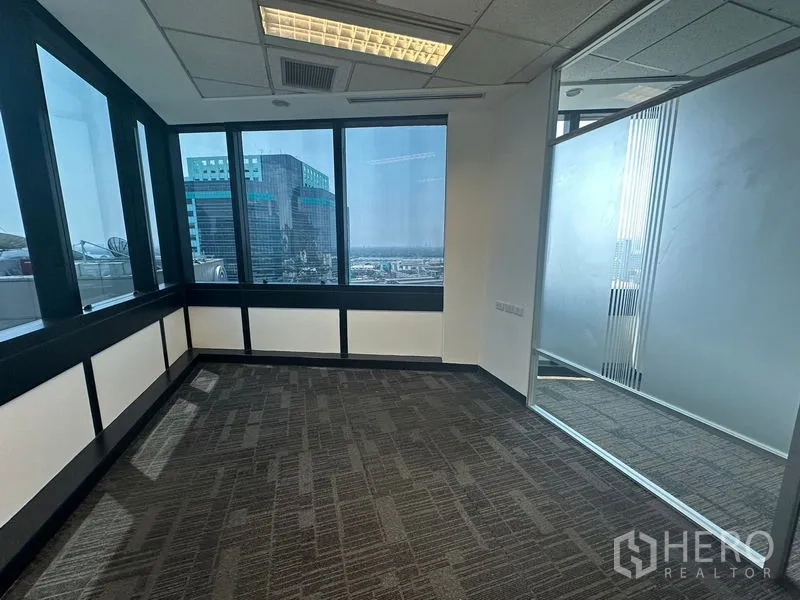 Office Space for rent in Khlong Toei, Bangkok - Corner office with wraparound windows and sliding glass partition.