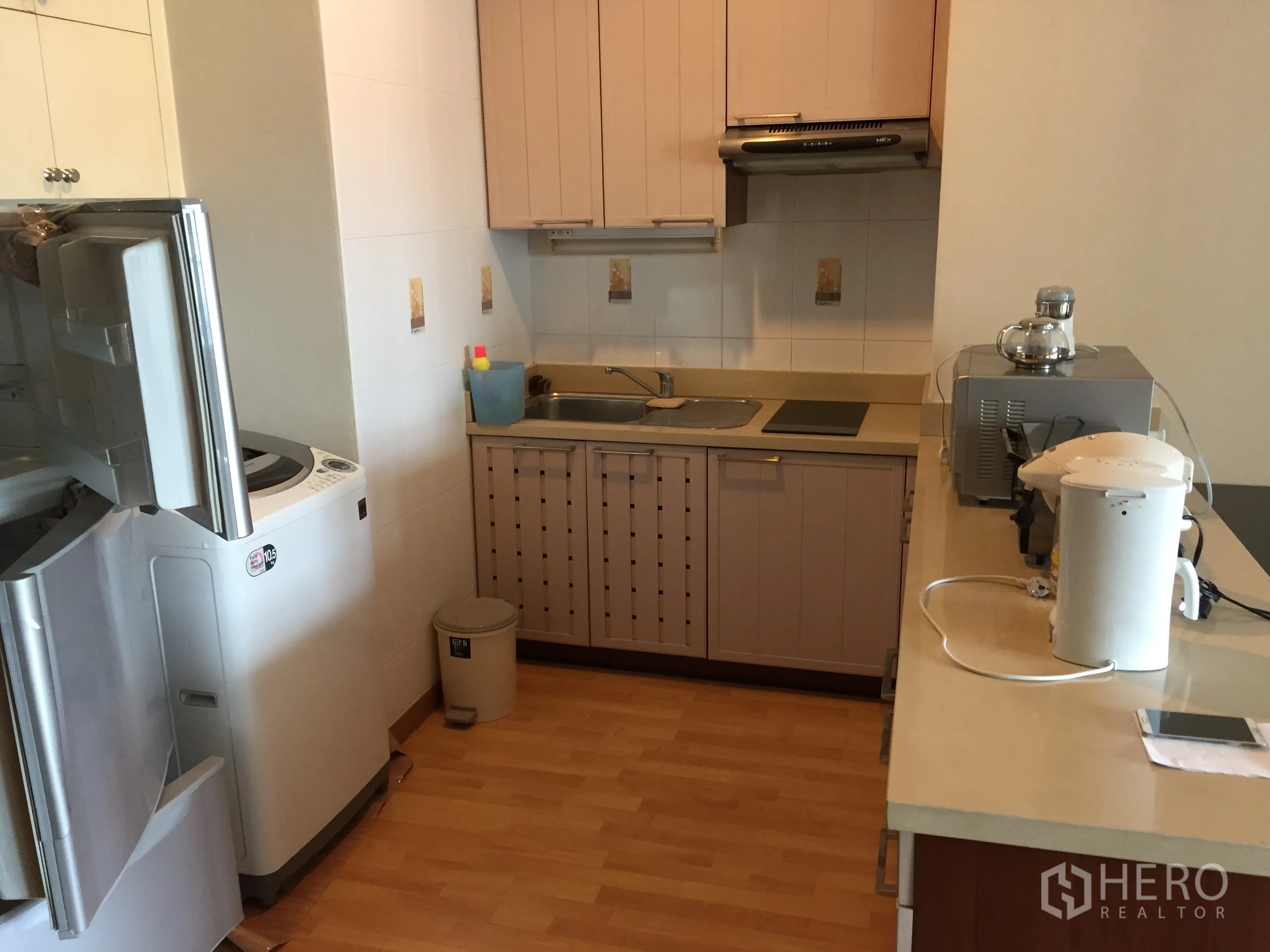 Condominium for rent in Khlong Toei, Bangkok - Compact fitted kitchen with cooktop, hood, sink, fridge and washing machine.