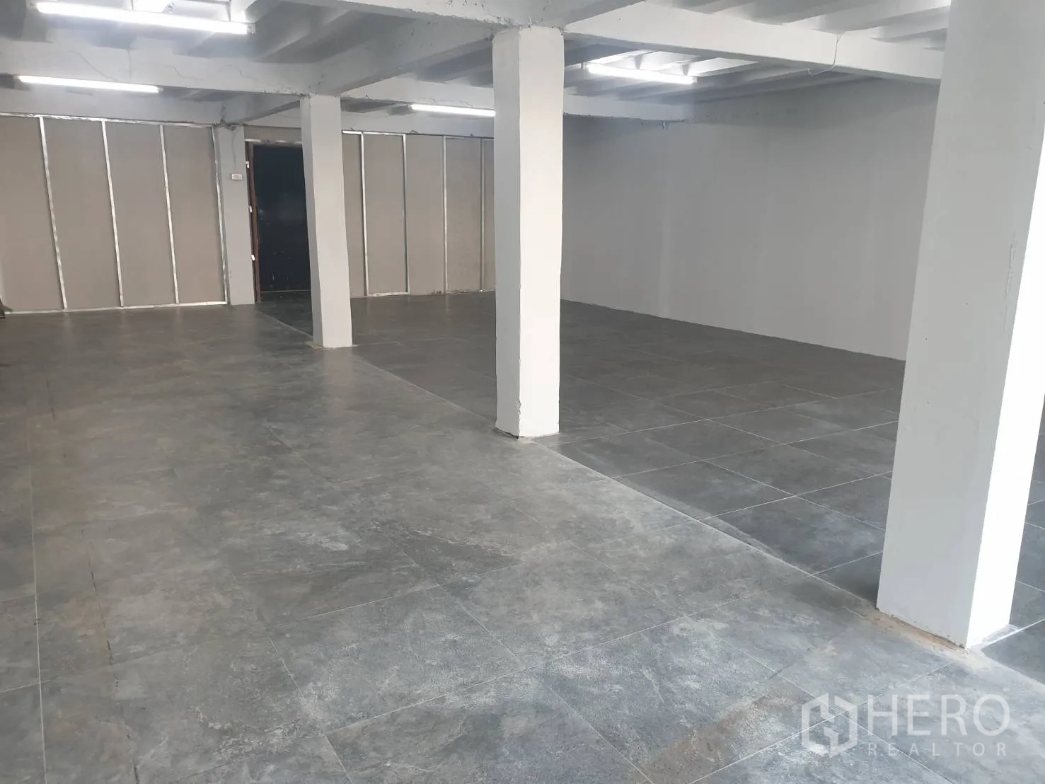 Retail Space for rent in Khlong Toei, Bangkok - Open-plan retail interior with grey tile flooring, white support columns and bright strip lighting.