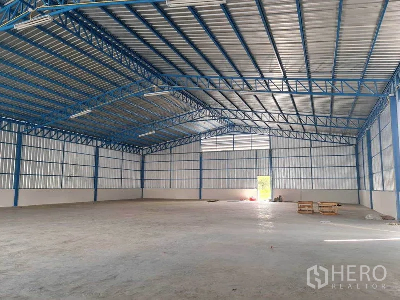 Warehouse for rent in Nong Chok, Bangkok - Spacious 500 sqm clear-span warehouse interior with blue steel trusses and concrete floor.