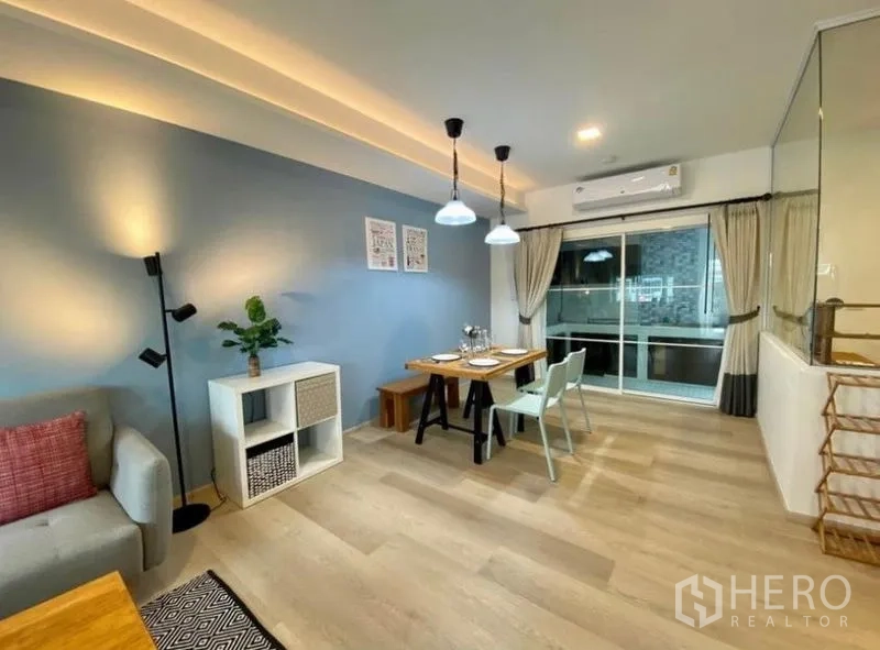 Townhouse for rent in Bang Phli, Samut Prakan - Open-plan living and dining space with blue accent wall, air conditioning and sliding glass door.