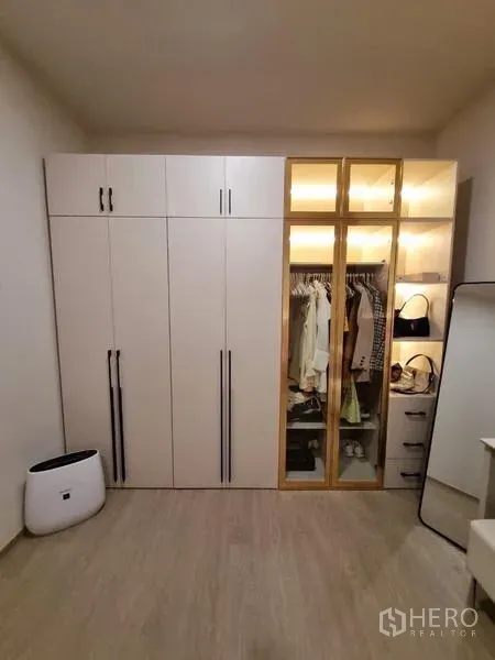 Townhouse for rent - Close-up of illuminated wardrobe system with glass doors and drawers.