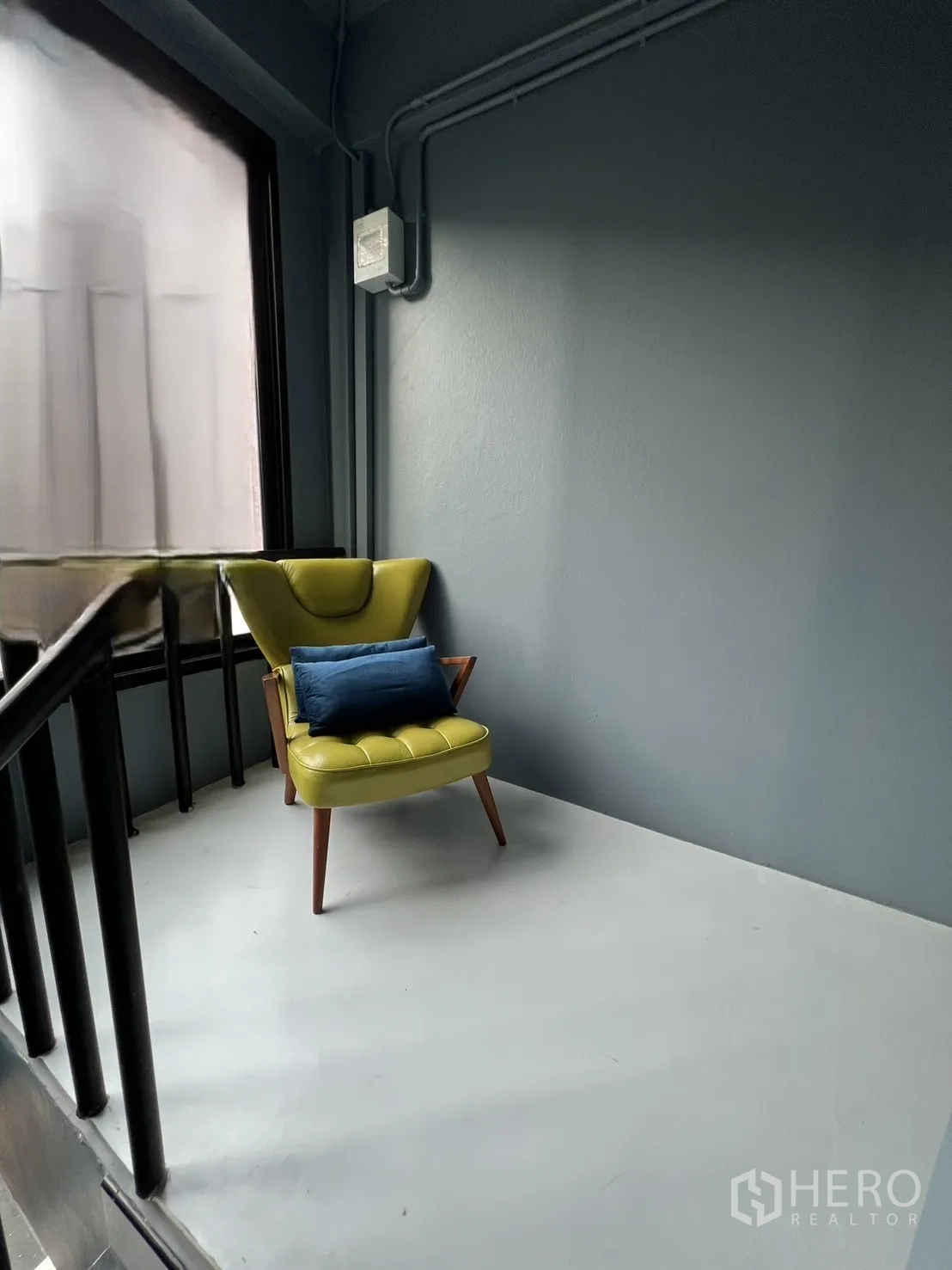 Shophouse for rent or sale in Watthana, Bangkok - Cozy reading nook with green armchair and blue cushion on the stair landing.