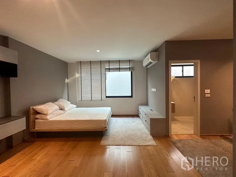 Townhouse for sale in Saphan Sung, Bangkok - Master bedroom with wood floors, air conditioning and en‑suite bathroom entrance.