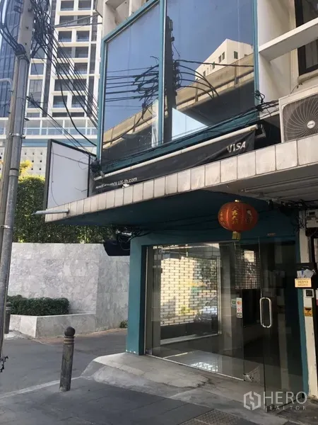 Retail Space for rent in Khlong Toei, Bangkok - Upper-floor corner glazing and glass panels above the street-level shop entrance.