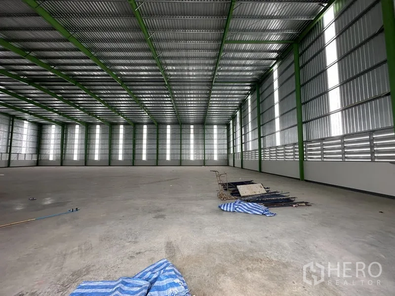 Warehouse for rent in Wang Noi, Phra Nakhon Si Ayutthaya - Clean concrete floor inside the warehouse with ventilation panels and some equipment.