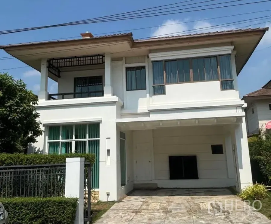 Detached House for rent in Bang Phli, Samut Prakan - Front facade of a two-storey house with shaded balcony and hedged garden.