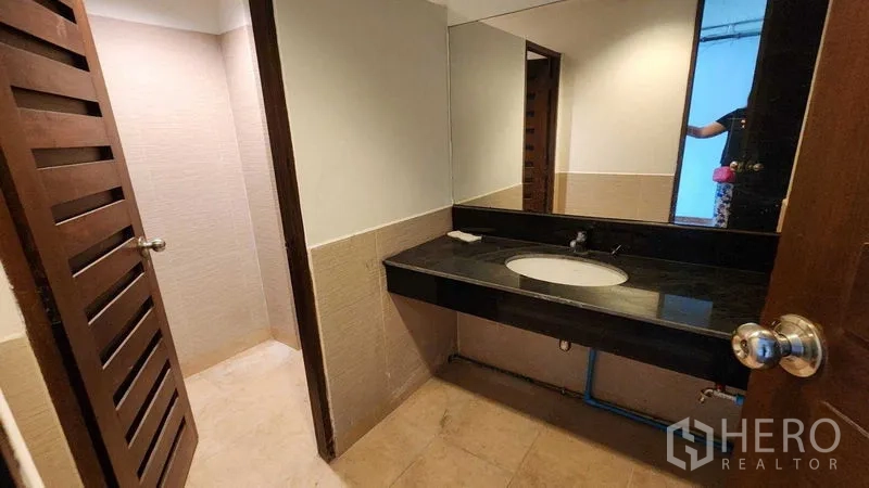 Shophouse for rent in Khlong Toei, Bangkok - Clean restroom with granite vanity, mirror, and light-colored tiles.