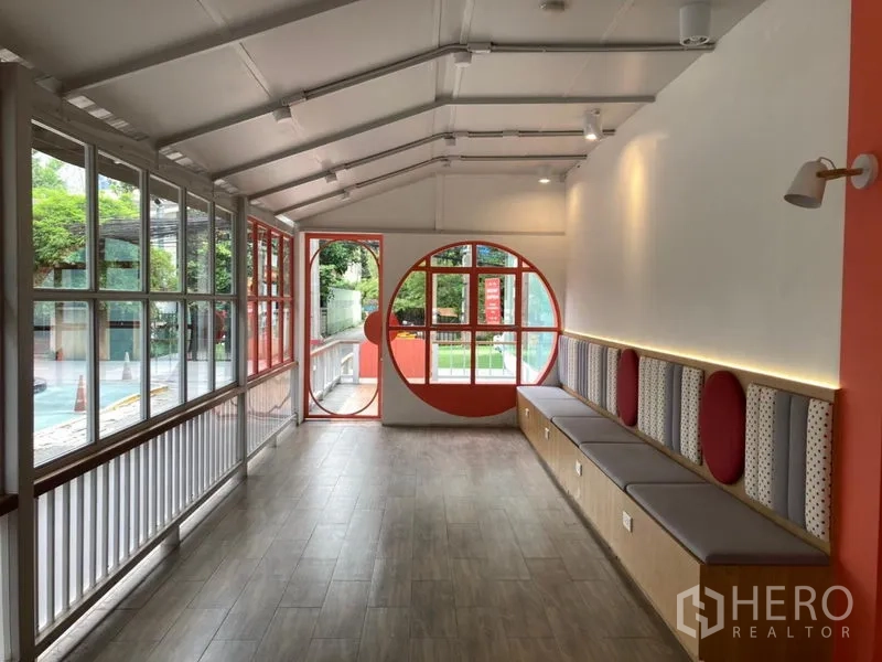 Retail Space for rent in Khlong Toei, Bangkok - Bright retail interior with wood-look floors, a round feature window, and built-in bench seating.