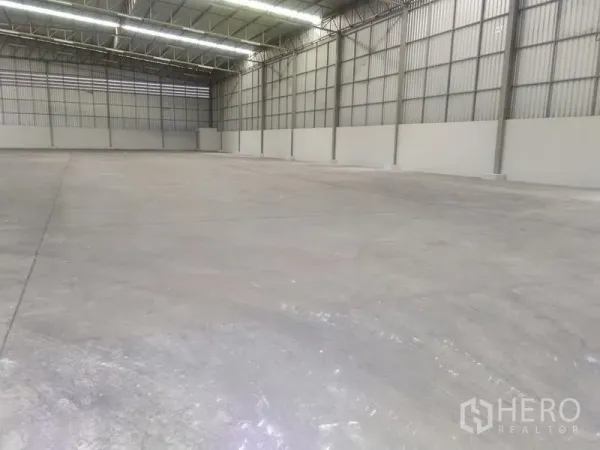 Warehouse for rent in Bang Phli, Samut Prakan - Spacious empty warehouse interior with high clear-span steel roof, bright strip lighting and concrete floor.