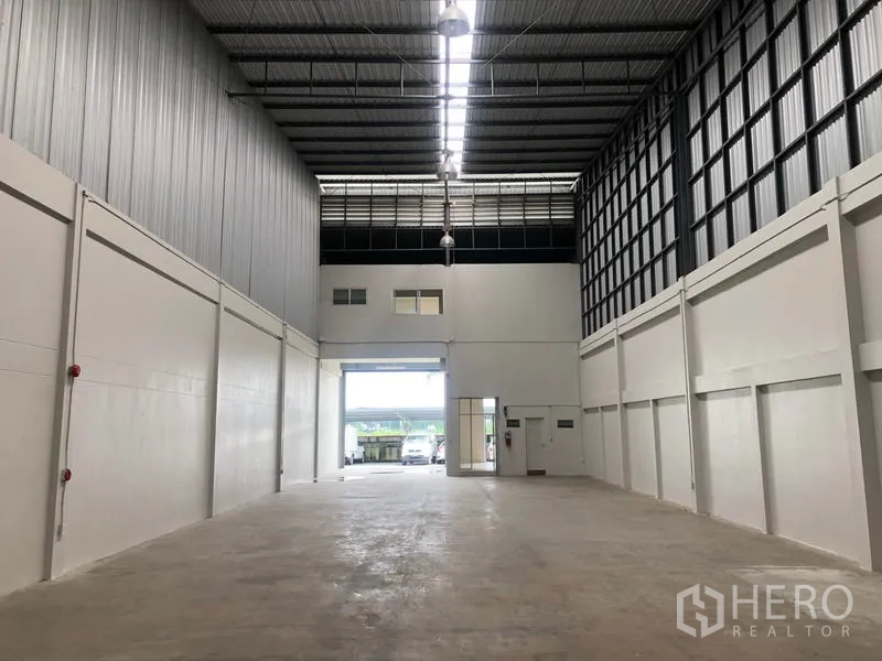 Factory for rent in Pak Kret, Nonthaburi - Warehouse interior looking toward the front shutter with skylights and pendant lights.
