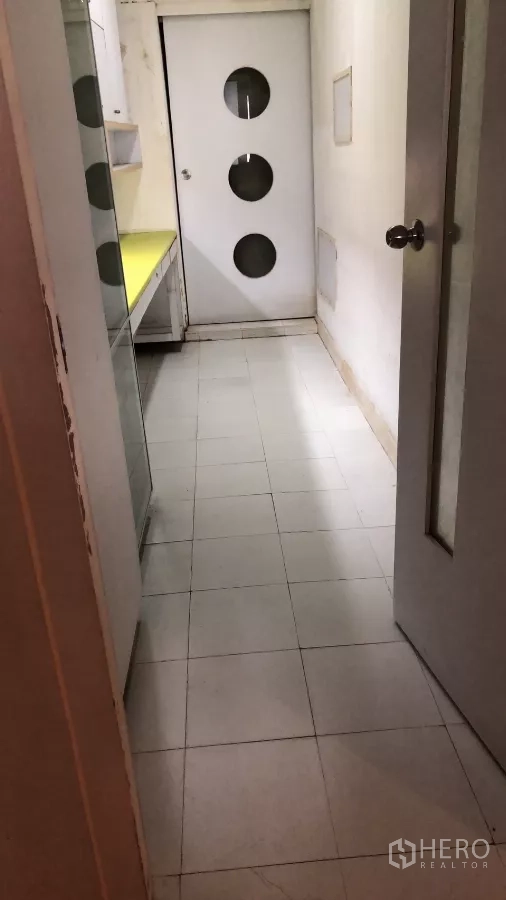 Shophouse for sale in Watthana, Bangkok - Service corridor with cabinets leading to a door with circular windows.
