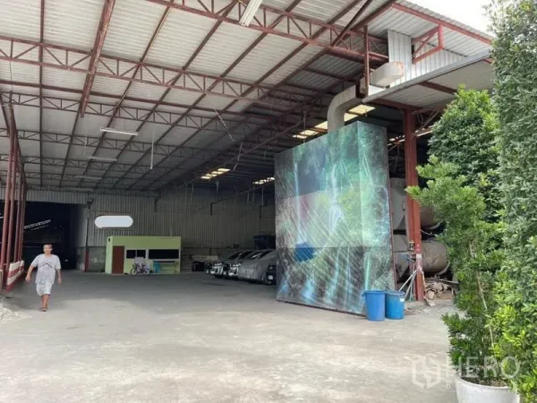 Warehouse for sale in Lam Luk Ka, Pathum Thani - Covered loading bay with high steel trusses, ventilation ducting, and open concrete floor inside the warehouse.
