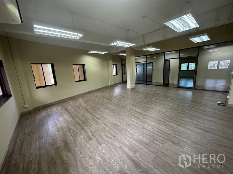 Office Space for rent in Chatuchak, Bangkok - Open-plan office with wood-look flooring, fluorescent grid lighting, multiple windows and glass-partition doors.