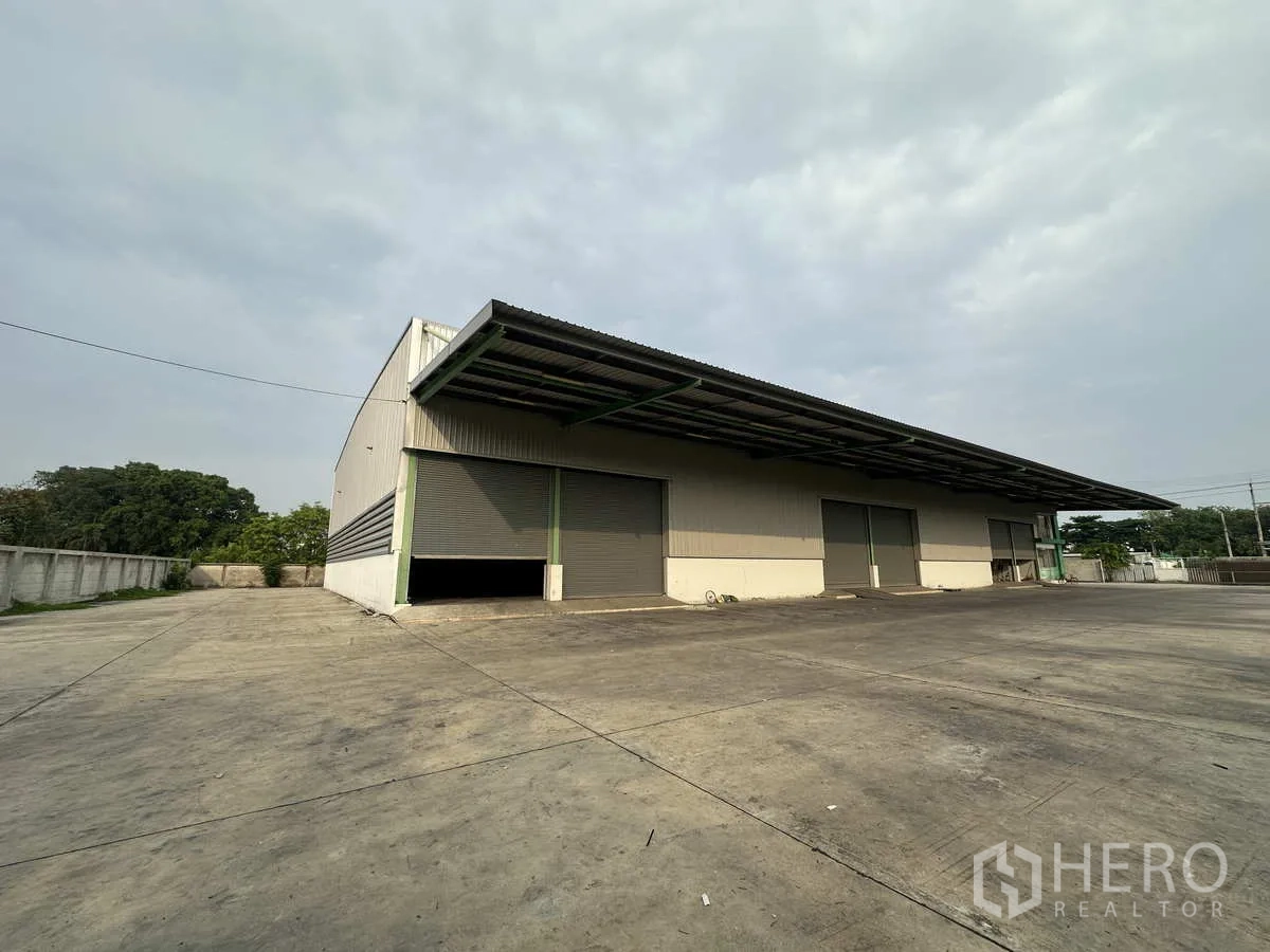 工厂 出租在Mueang Samut Prakan, Samut Prakan - 仓库侧面，带顶装卸平台、卷闸门与围墙场地。