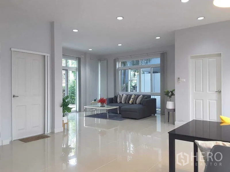 Detached House for rent in Lam Luk Ka, Pathum Thani - Open-plan family area with recessed lighting, sofa set and glossy tiled floor.